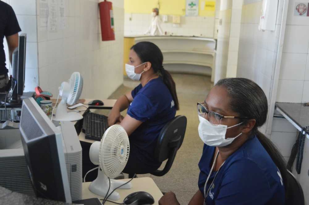 Atendentes da recepção da unidade de saúde têm que tarbalhar de máscaras (Foto: Portal Infonet)