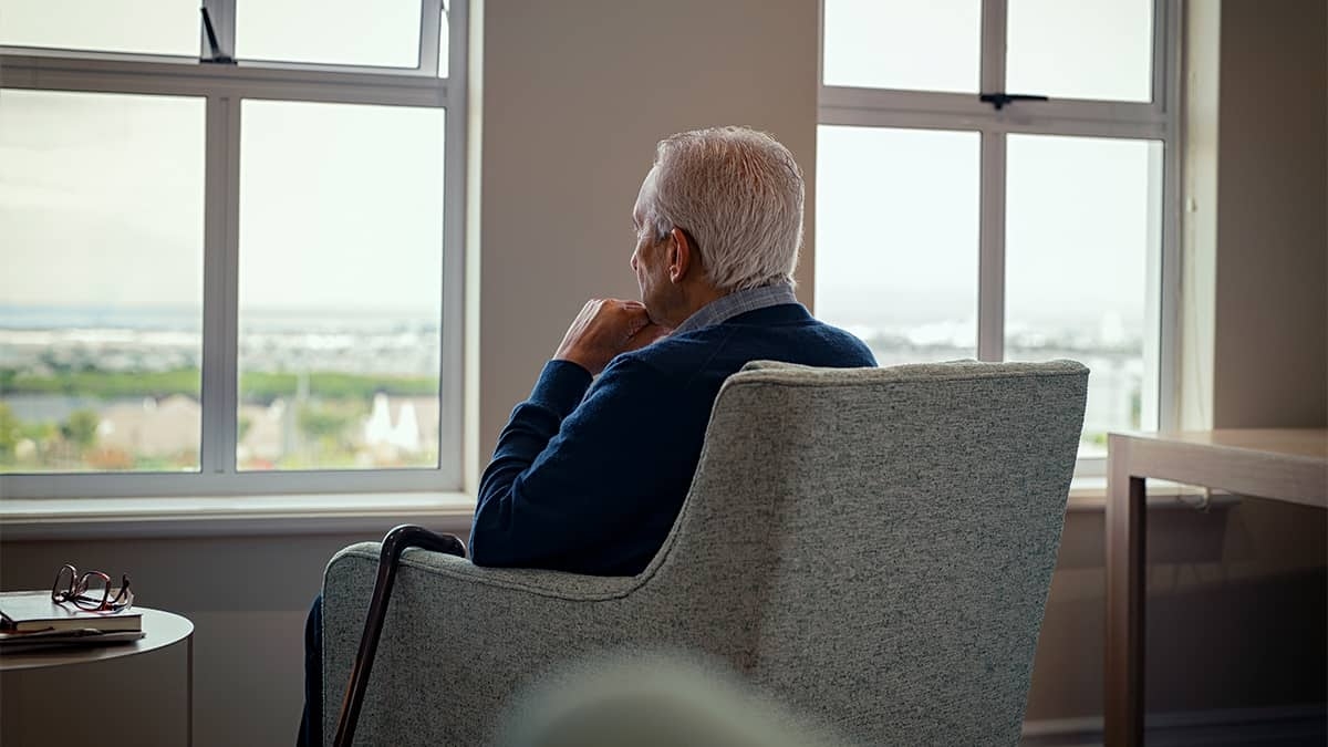 Idoso com Alzheimer sentado em poltrona olhando para janela - Imagem: Ground Picture | Shutterstock